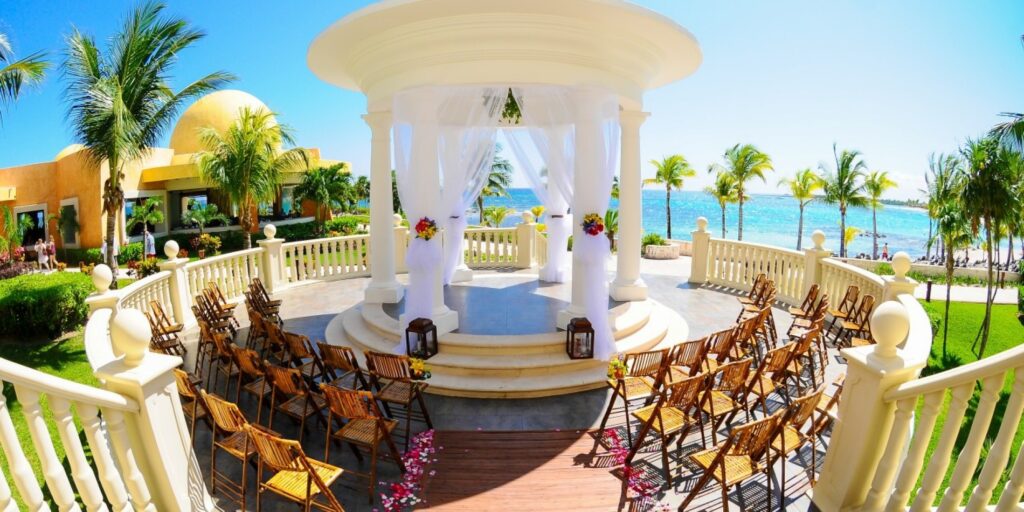 Wedding chairs set up in front of a white pavilion overlooking the ocean at Barcelo Maya Palace Hotel. One of the locations we've traveled to for planning a destination wedding.