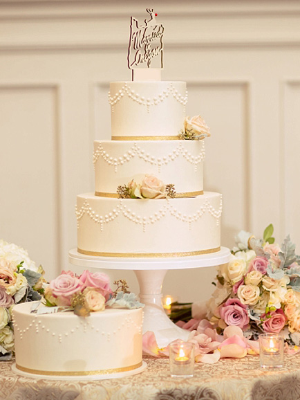 three tier wedding cake on table, surrounded by flowers