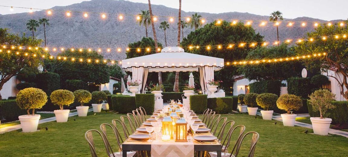 Image ID: a dining table set in the middle of a lawn, with twinkle lights strung above.