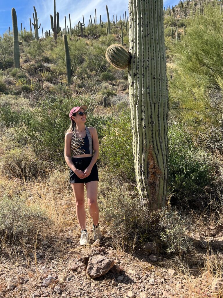EJP Events coordinator Katherine O'Brien stands next to a desert cactus in Tuscon, Arizona.