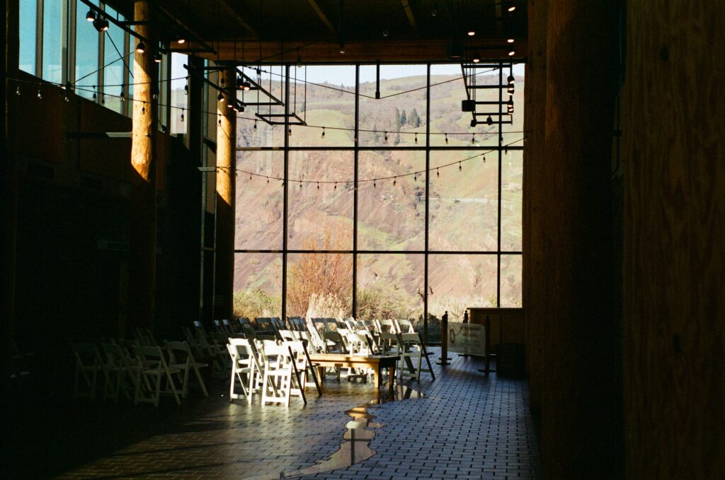 Interior hallway with chairs set up for wedding or event, in front of big glass window with view of Columbia Gorge