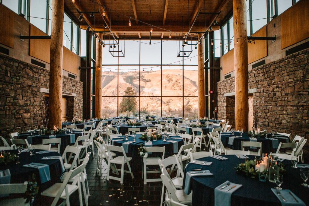 Interior hallway with tables set up for wedding or event, in front of big glass window with view of Columbia Gorge