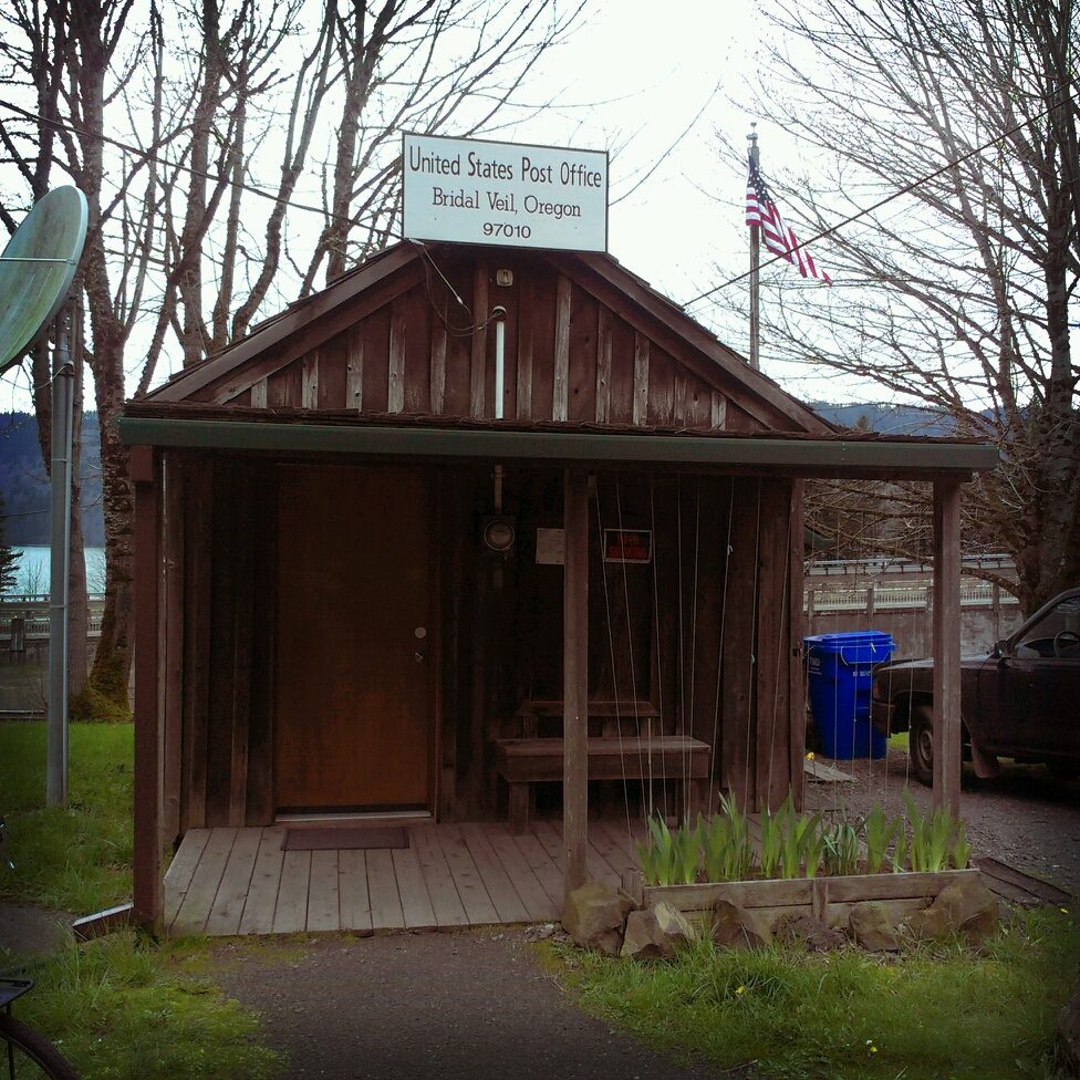 Front view of Bridal Veil Post Office, a small wooden house of about 10 feet by 10 feet, with front porch.
